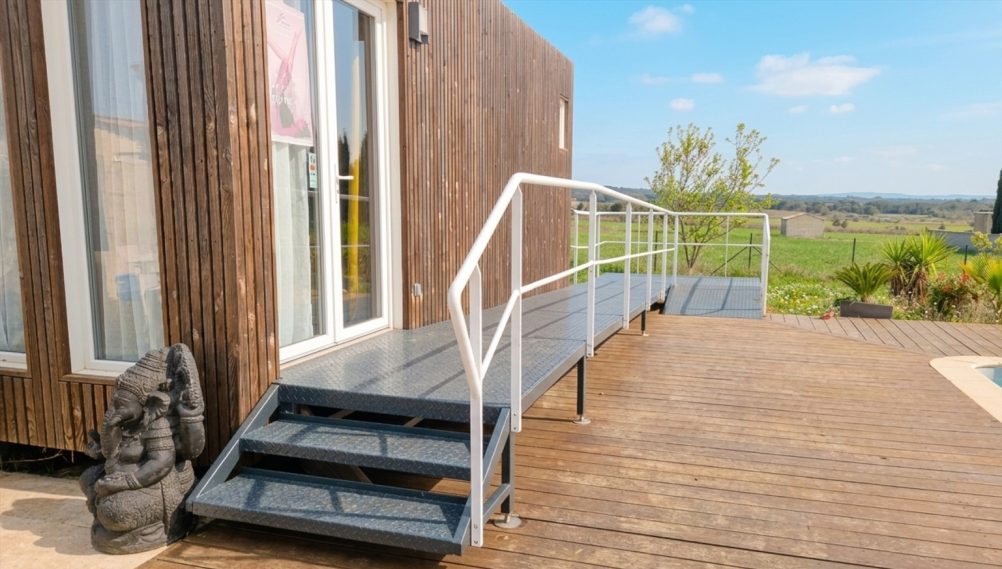 Accès PMR Studio privé Rampe d'accès menant à une terrasse en bois près d'une construction moderne.